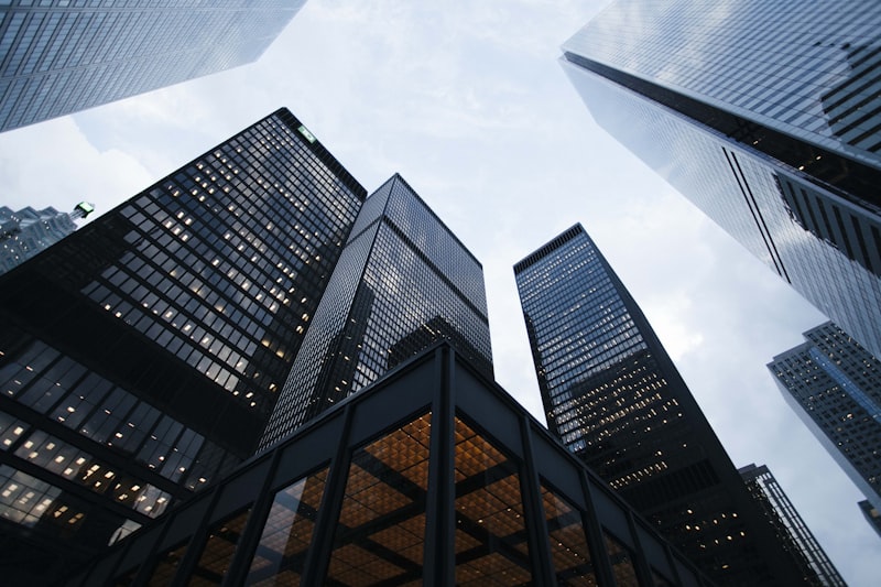 Sede corporativa moderna de cristal vista desde abajo contra un cielo azul — la superficie multimercado que EmpCo incorpora al ámbito de aplicación el 27 de septiembre de 2026