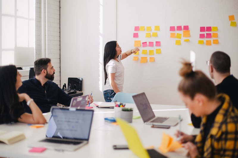 Equipo interdepartamental colaborando en torno a notas adhesivas y un panel de estrategia — clasificando por riesgo las afirmaciones ambientales durante la auditoría EmpCo del tercer trimestre