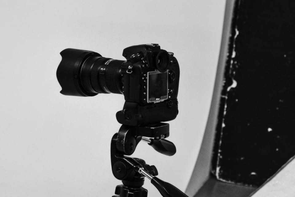Eine Kamera auf einem Stativ in einem weißen Fotostudio, wie dort, wo Produktbilder und Infografiken entstehen