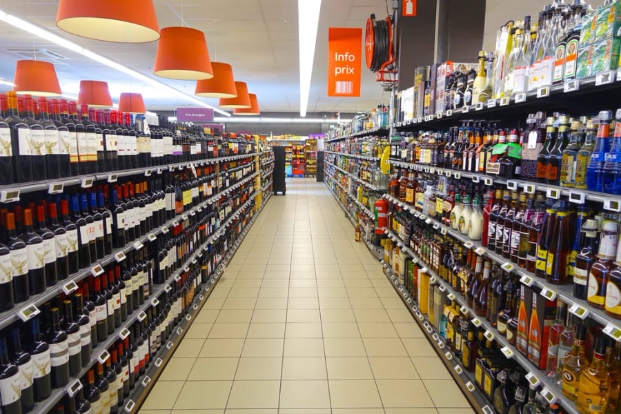 Ein langer Supermarktgang mit verpackten Flaschen auf beiden Seiten, Waren, deren Etiketten vor den neuen Regeln gedruckt wurden