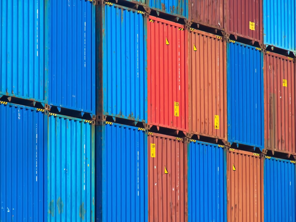 Container marittimi blu e rossi impilati, merce in arrivo da fuori dell'UE