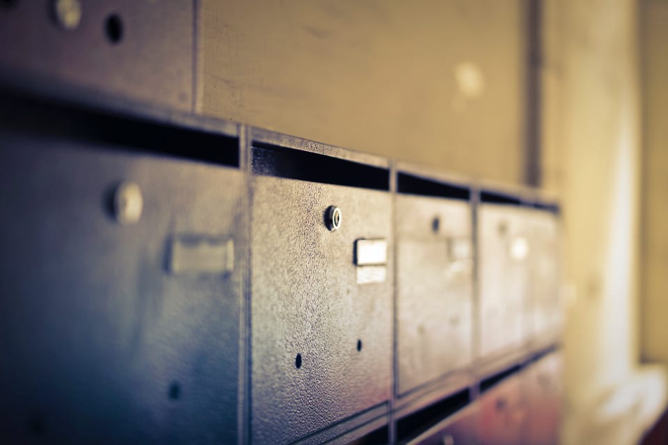Una fila de buzones metálicos en un pasillo, para recordar que un fabricante necesita una dirección postal y electrónica reales