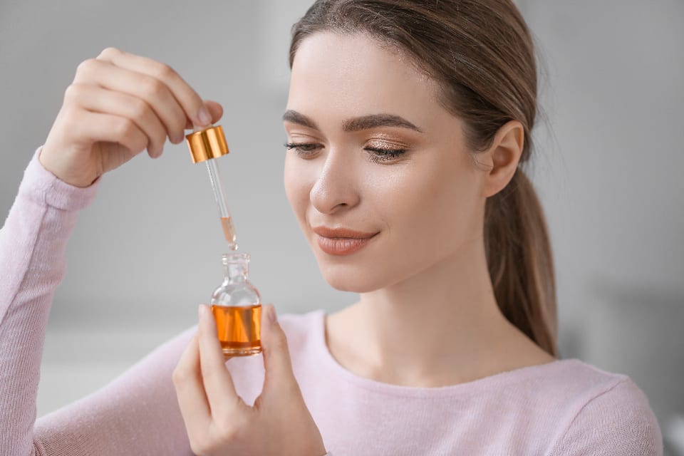 Una donna tiene un flacone cosmetico con contagocce, un prodotto le cui precauzioni d'uso vanno nella scheda prodotto