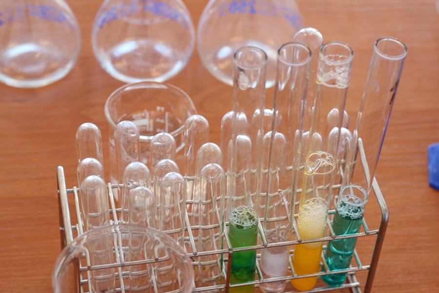 Reagenzgläser und Laborglas in einem Gestell, wo Aussagen zu biologischer Abbaubarkeit und Kompostierbarkeit nach einer Norm geprüft werden