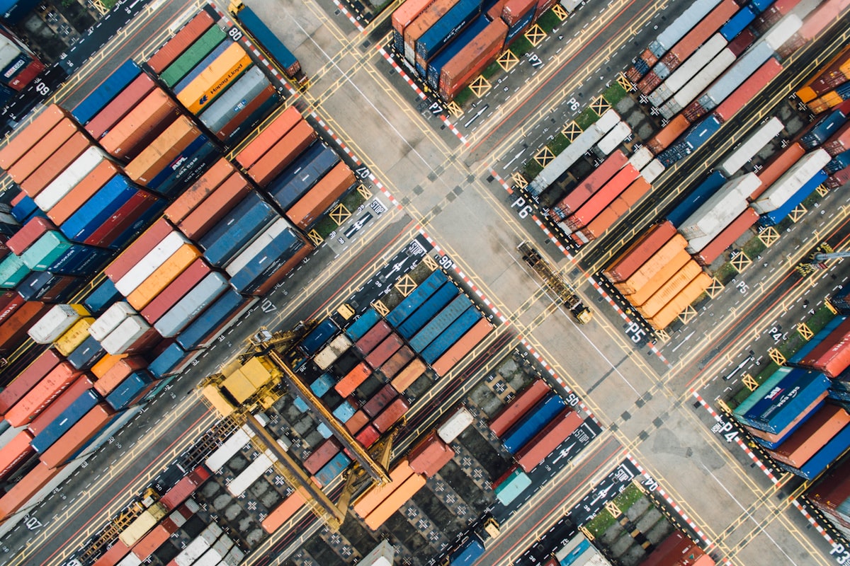 Vista aerea di container impilati in un grande porto commerciale — il volume del commercio transfrontaliero che amplifica l'esposizione EmpCo dei venditori statunitensi